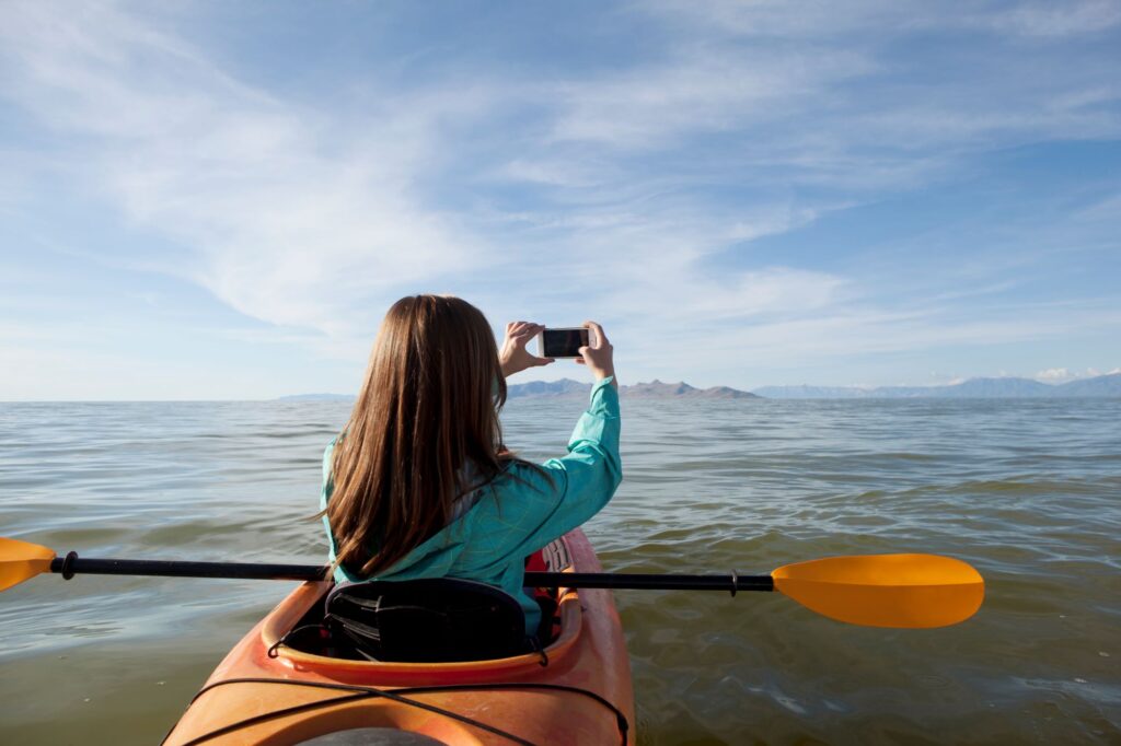 woman taking a picture to the water from a kayak