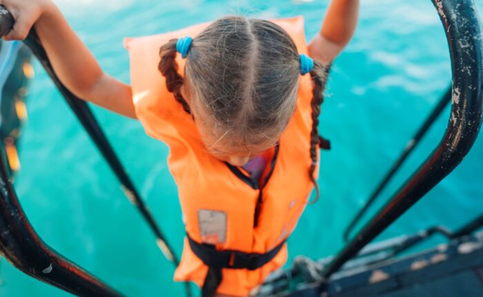 a child wearing a lifejacket climbing up a boat