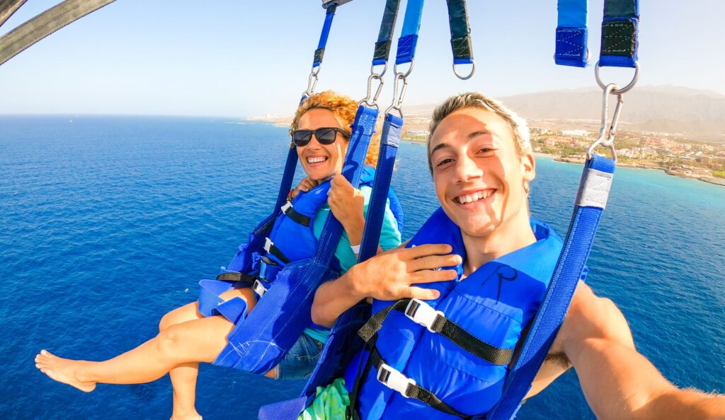 close up selfie of two smiling people parasailing