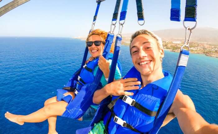 close up selfie of two smiling people parasailing
