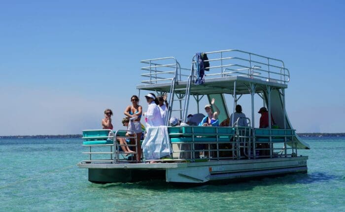 Double decker pontoon boat with an upper deck and water slide anchored at Crab Island in Destin, FL